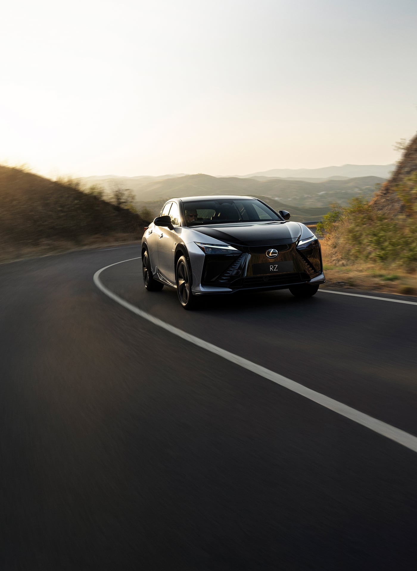 Lexus RZ driving along a road at sunset